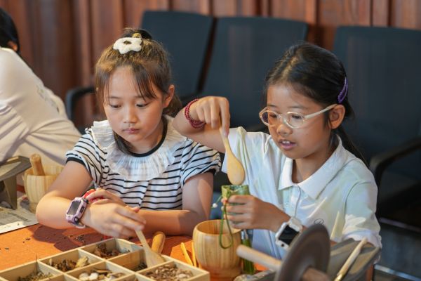 2025年7月25日，貴州省銅仁市碧江區(qū)銅仁博物館，兩名小朋友正在將研磨完成的中藥裝進香包。申逸愷 攝